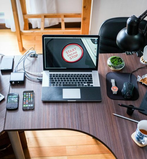 A contemporary office desk setup with laptops, gadgets, and accessories, creating a tech-savvy workplace.