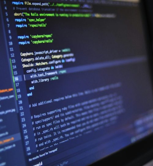 Close-up of a computer screen displaying programming code in a dark environment.